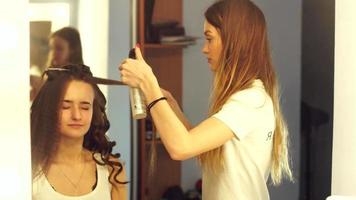 young hair stylist make hairstyle with beautiful woman at salon video