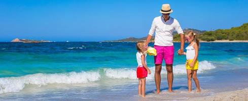 Little girls and happy dad having fun during tropical vacation photo