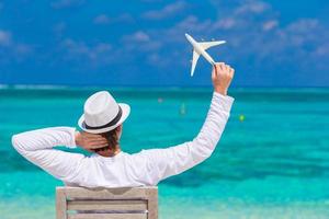 Young man with miniature of an airplane at tropical beach photo