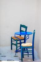 silla azul y mesa en la calle del típico pueblo tradicional griego en la isla de mykonos, grecia, europa foto