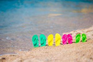 Family colorful flip flops on beach in front of the sea photo