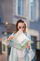 Happy young woman with a city map in Europe. Travel tourist woman with map in Prague outdoors during holidays in Europe. photo