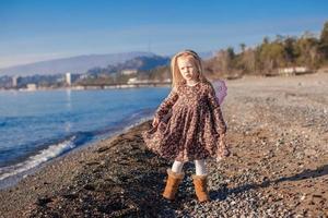 Adorable Little girl on the beach in a winter sunny day photo