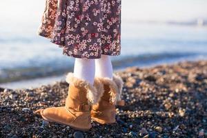 primer plano de las piernas niña en acogedoras botas de piel de fondo el mar foto