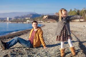 Young father and his little adorable daughter having fun on winter beach photo