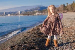 Adorable little girl with butterfly wings running along the beach in a winter sunny day photo