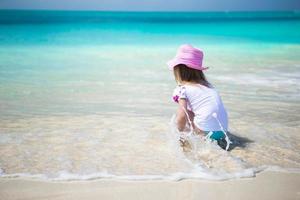 linda niña pequeña jugando en aguas poco profundas en una playa exótica foto