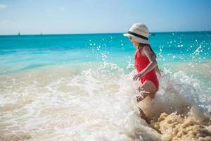 Adorable little girl play with water at beach during caribbean vacation photo