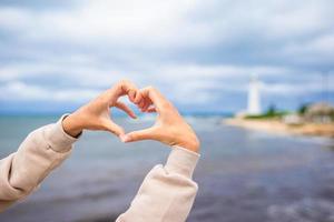 Female hands in the form of heart against the lighthouse photo