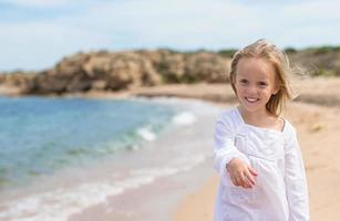 Adorable little girl have fun at tropical beach photo