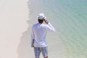 joven hablando por teléfono celular en la playa tropical foto