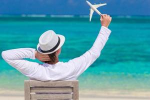 Young man with miniature of an airplane at tropical beach photo