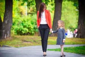 Mother brings her daughter to school. Adorable little girl feeling very excited about going back to school photo