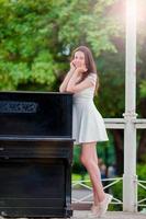 hermosa chica disfruta el fin de semana de verano en el parque al aire libre cerca del gran piano. mujer joven de vacaciones al aire libre sonriendo feliz. foto