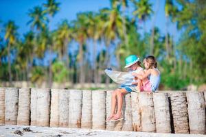 Adorable little girls with big map of island on beach photo