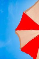 Closeup of a red andd yellow sun umbrella on background of blue sky photo