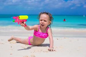 Happy little girl playing with toys at beach during vacation photo