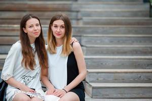 Caucasian girls enjoy summer weekend background big bridge. Young tourist friends traveling on holidays outdoors smiling happy. photo