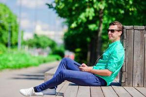 Boy listening music by smartphone on summer holidays. Young attractive tourist with mobile phone outdoors enjoying holidays. photo