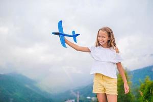 niña feliz con avión de juguete en las manos en las montañas foto