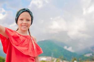 Beautiful happy little girl in mountains in the background of fog photo