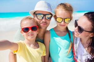 joven y hermosa familia tomando un retrato de selfie en la playa foto