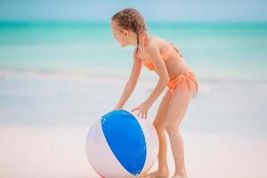 adorable niña jugando en la playa con pelota foto