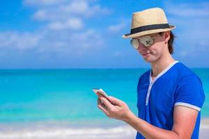 Young businessman with his phone on beach vacation photo