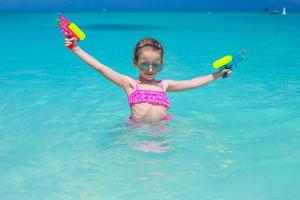 Happy little girl playing at beach during caribbean vacation photo