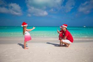 Cute girl making photo on phone father and sister at the beach