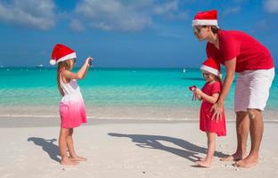 Little girl making photo on phone of her family at the beach