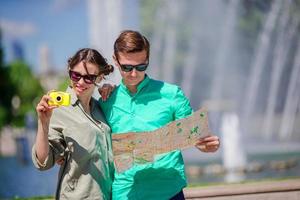 jóvenes amigos turistas que viajan de vacaciones en europa sonriendo felices. chica tomando fotos en el parque y hombre con mapa de la ciudad en busca de atracciones