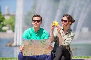 jóvenes amigos turistas que viajan de vacaciones en europa sonriendo felices. familia caucásica con mapa de la ciudad en busca de atracciones foto