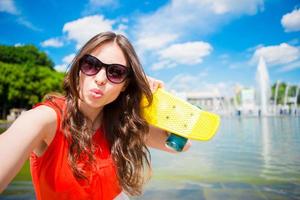 Young girl having fun with skateboard in the park. Lifestyle portrait of young positive woman having fun and enjoy warm weather. photo