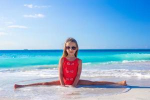 Cute gymnastic little girl doing her exercises on tropical beach photo