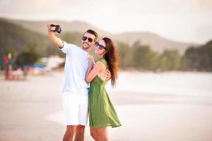 pareja feliz tomando una foto en la playa blanca en vacaciones de luna de miel