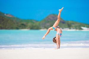 Active little girl at beach having a lot of fun. Sporty kid making the wheel on the seashore photo