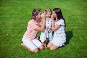 Young family of three sitting on the grass and have fun photo