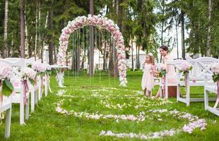 bancos de boda con invitados y arco de flores para ceremonia al aire libre foto