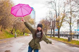 Young woman walking with umbrella in autumn rainy day photo
