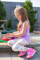 niña linda jugando en el arenero con juguetes en el patio foto