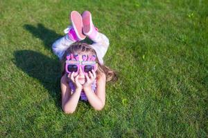 Adorable little girl in Happy Birthday glasses smiling outdoor photo