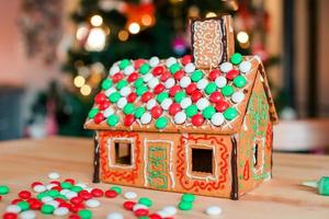 Gingerbread fairy house on a background of bright Christmas tree with garland photo