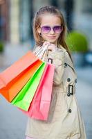 Portrait of adorable little girl walking with shopping bags outdoors photo