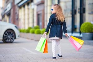 Adorable little girl having fun with shopping bags outdoors photo