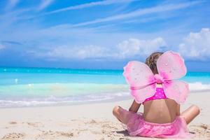 linda niña con alas de mariposa en vacaciones en la playa foto