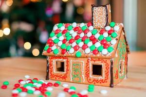 Gingerbread fairy house on a background of bright Christmas tree with garland photo