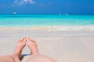 cerca de pies femeninos en la playa de arena blanca foto