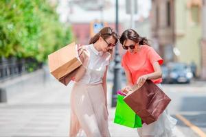 mujeres jóvenes felices con bolsas de compras disfrutan de su compra caminando por la calle de la ciudad. concepto de venta, consumismo y personas.