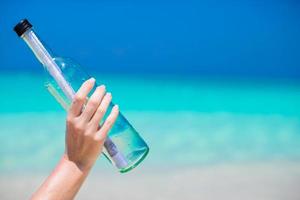 Bottle with a message in the hand background blue sky photo